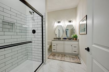 A bathroom with a white tiled shower and a vanity with a mirror above it.